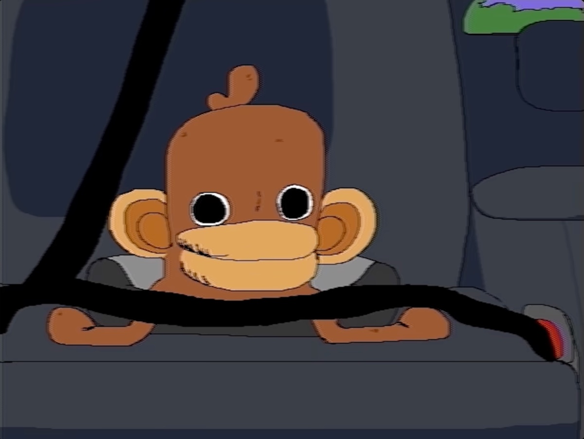 Onkey buckled into the back seat of a car, seatbelt across his chest, staring straight ahead.